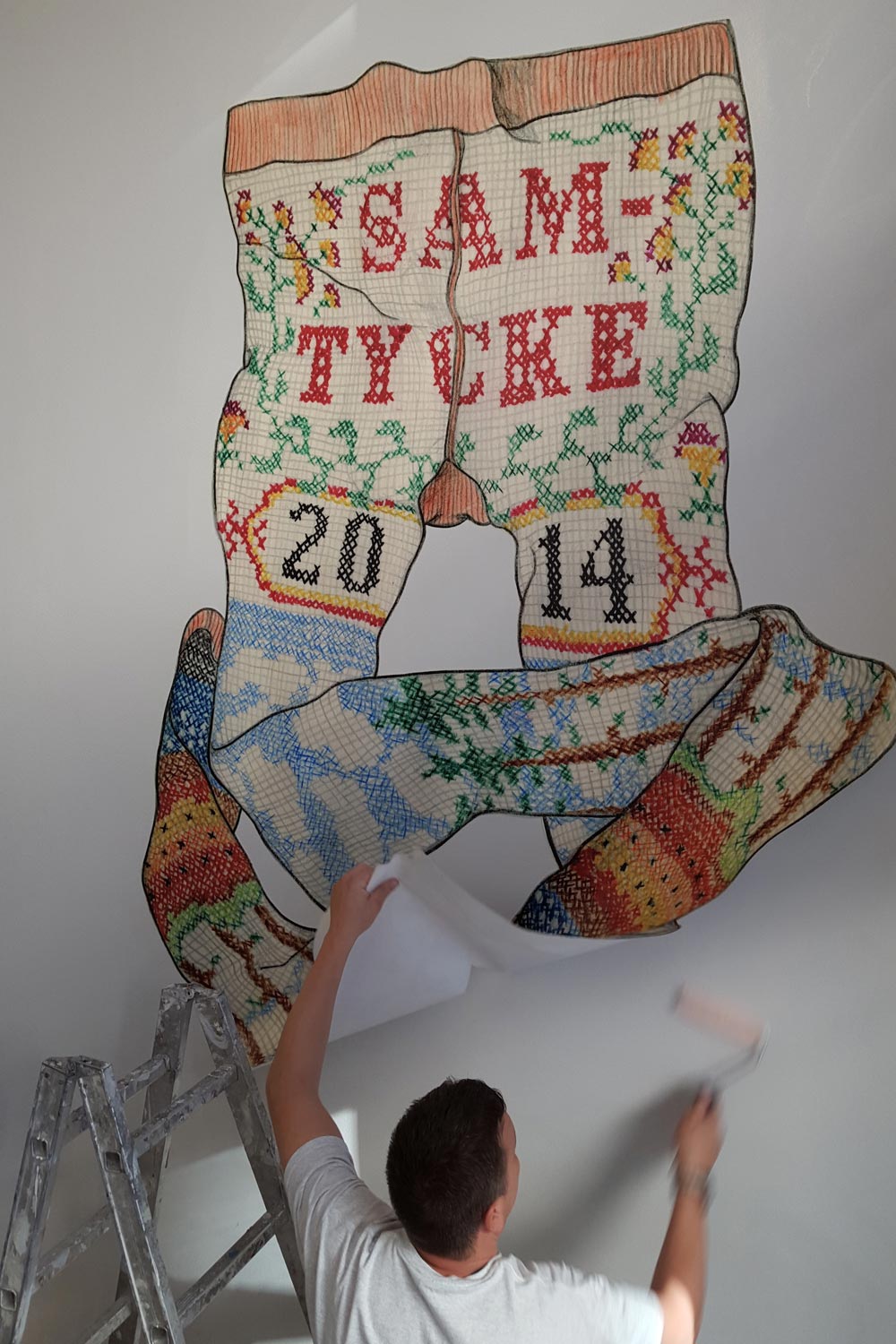 En person fäster en tavla på väggen med klister